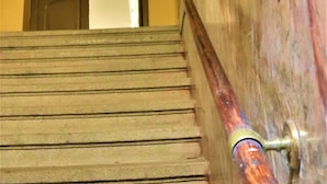 A staircase with a handrail, a door at the top, and a wall with a textured surface. - Flowers apartments (Prague)
