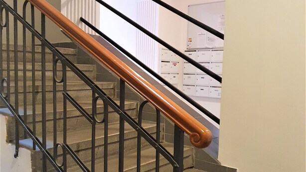 A staircase with black metal railings and wooden handrails, leading to a room with white walls and a red ceiling. - Reznicka Apartments (Prague)
