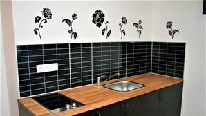 A kitchen with black tiles, a wooden countertop, and a sink. - Reznicka Apartments (Prague)