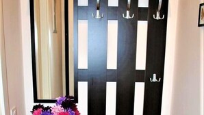 A black and white console table with a mirror above it, a vase of flowers, and a black partition with hooks. - Reznicka Apartments (Prague)