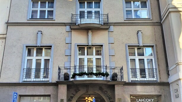 A multi-story building with a central entrance, balconies with railings, and a ground-level shop. - Epstein Apartments (Prague)