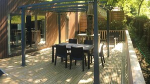 Una terraza cubierta al aire libre con mesa y sillas, un pérgola y un deck de madera.