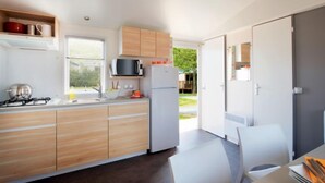 Una cocina moderna con armarios de madera, una estufa a gas, un microondas y un refrigerador.