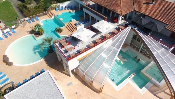 Zona de piscina en la azotea con varias piscinas, tumbonas y un área de estar cubierta.