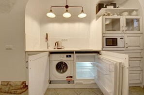 Une cuisine compacte équipée d’un lave-linge et d’un sèche-linge intégrés, d’un four à micro-ondes et d’une machine à café.