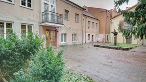 En gårdsplads med belagt areal, en bygning med balkon og en statue.