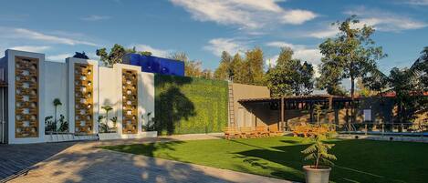 A modern outdoor area with a paved walkway, seating, and a green lawn.