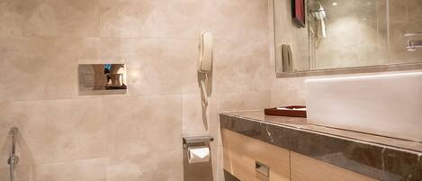 Une salle de bain moderne avec un grand miroir, des toilettes blanches, un lavabo et une poubelle.
