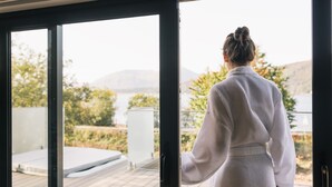 A person standing at a glass door with a view of a deck and outdoor area. - SeaBeds Luxury Lookouts with Hot Tubs (Ballachulish)