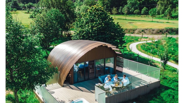 A modern outdoor villa with a curved roof, a glass-enclosed patio, and a hot tub. - SeaBeds Luxury Lookouts with Hot Tubs (Ballachulish)