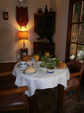 A dining table set with plates, glasses, and a plant, surrounded by wooden chairs. - Hotel Albucasis (Córdoba)