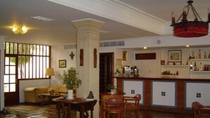 Amplia sala de estar con una mesa de comedor, sillas, un sofá y una zona de bar con estantes llenos de botellas.
