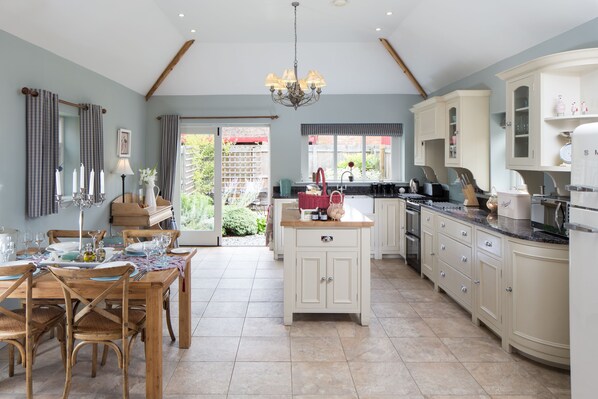 A spacious kitchen with wooden cabinetry, a central island, and a dining area with a table set for four.