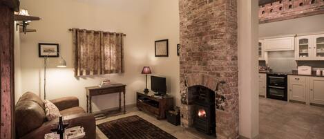 A cozy living room with a fireplace, a sofa, a coffee table, and a television.