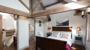 A bedroom with a wooden bed, a nightstand, a lamp, and a painting on the wall. - The Dovecote Barns (York)