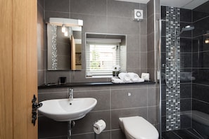 A modern bathroom with a large sink, a toilet, and a shower area.