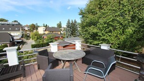 A deck with outdoor furniture, including a round table and chairs, a grill, and a view of the neighborhood. - Haus Krabbe (Göhren)