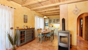 A cozy kitchen with a dining area, wooden ceiling beams, and a stone wall. - Haus Krabbe (Göhren)