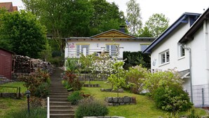 Un barrio residencial con una casa que tiene un jardín delantero, una escalera que sube a la casa y un edificio vecino.