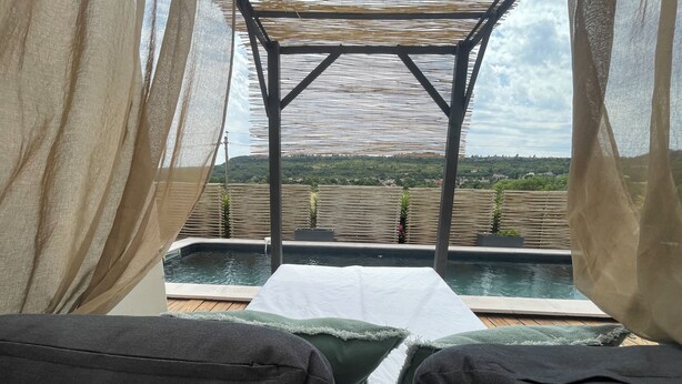 A poolside view with a pergola and a view of the countryside.