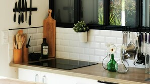 A kitchen with a black-framed window, a hanging knife rack, a wooden cutting board, and a potted plant.