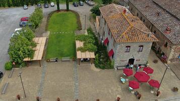Un área de estar al aire libre con mesas y sombrillas, un patio empedrado y un edificio con techo de tejas.