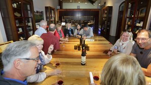 A group of people seated around a wooden table in a room with wooden cabinets and a wine rack in the background. - Brolio Agriroom (Gaiole in Chianti)