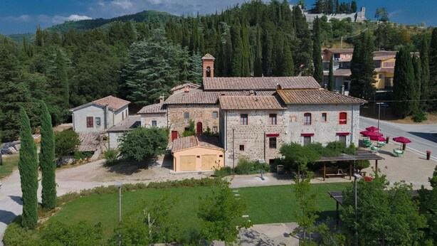 A stone building with a tiled roof, surrounded by greenery and a clear sky. - Brolio Agriroom (Gaiole in Chianti)