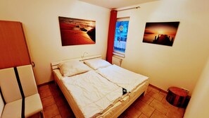 Ein Schlafzimmer mit einem Bett, einem Sessel und zwei Bildern an der Wand.