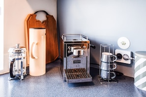 A kitchen with a coffee machine, a kettle, a coffee press, and a kettle holder. - Apartment A32 (Reykjavik)