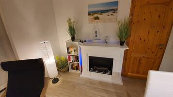 A cozy living room with a fireplace, a bookshelf, and a nautical-themed decor.