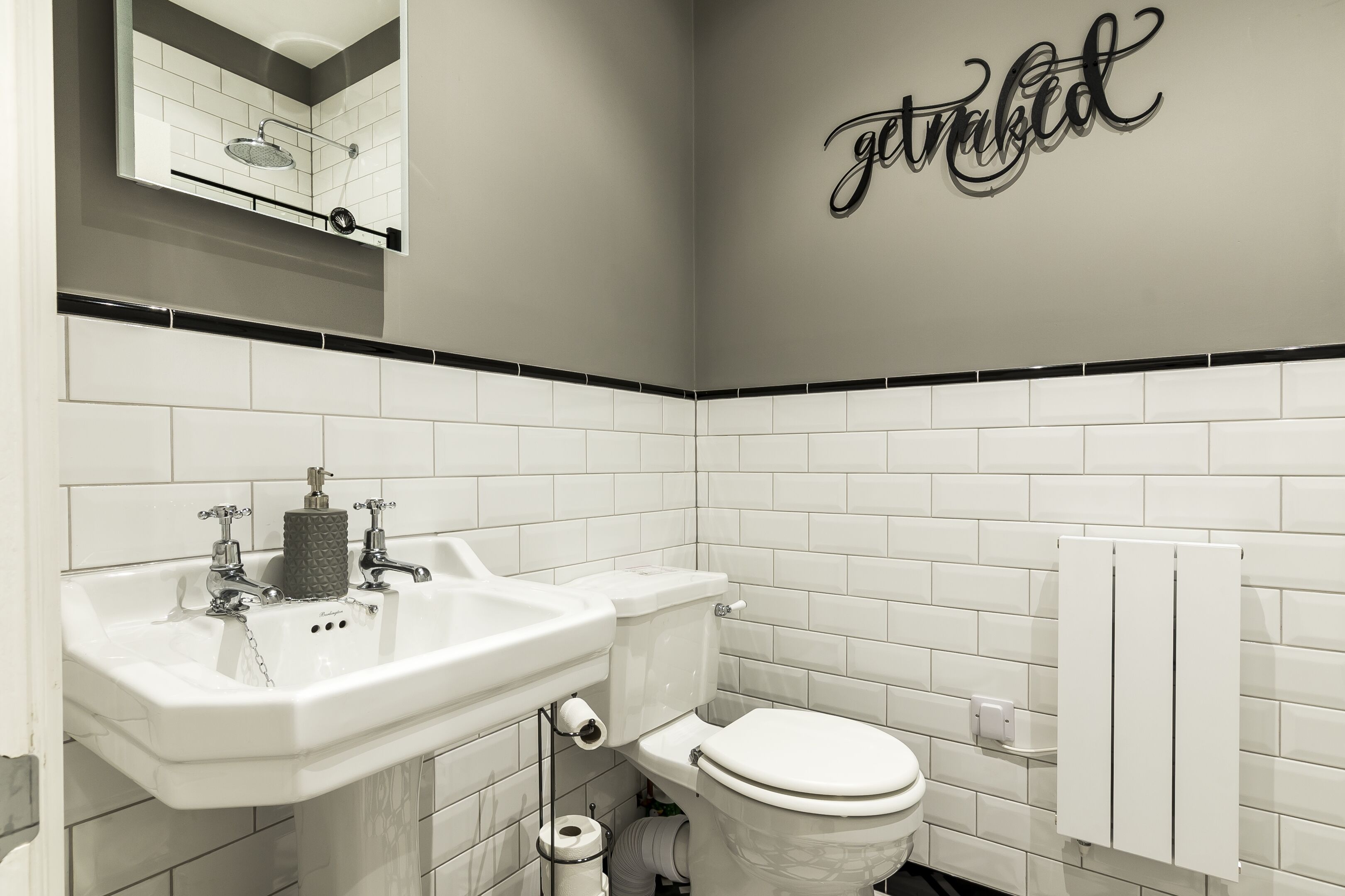 A modern bathroom with a white sink, toilet, and a towel rack.