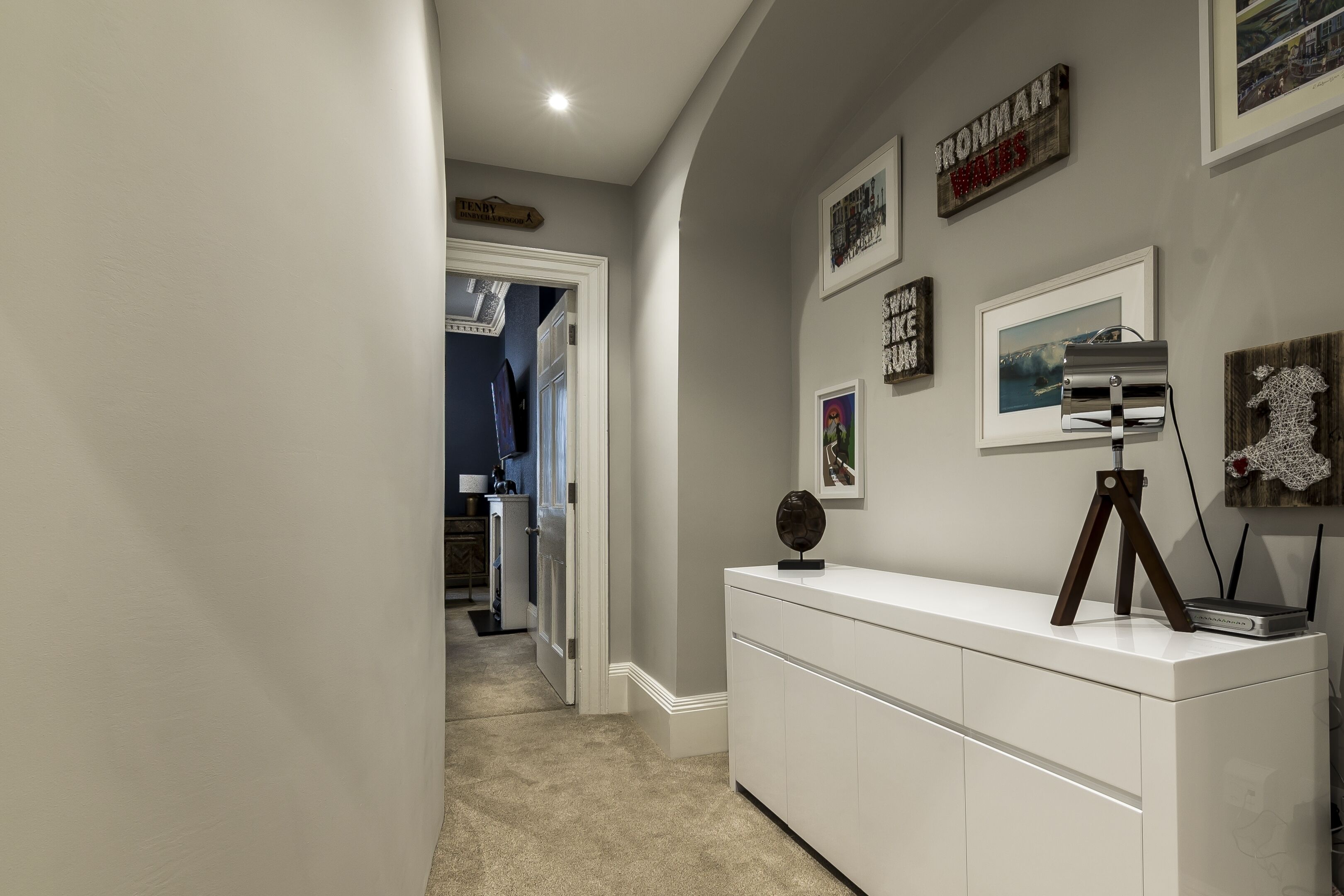 A hallway with a white console table, framed artwork, and a sign that reads "IRONMAN WILDCATS."
