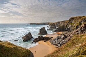 A coastal landscape with rocky cliffs, a sandy beach, and the ocean.