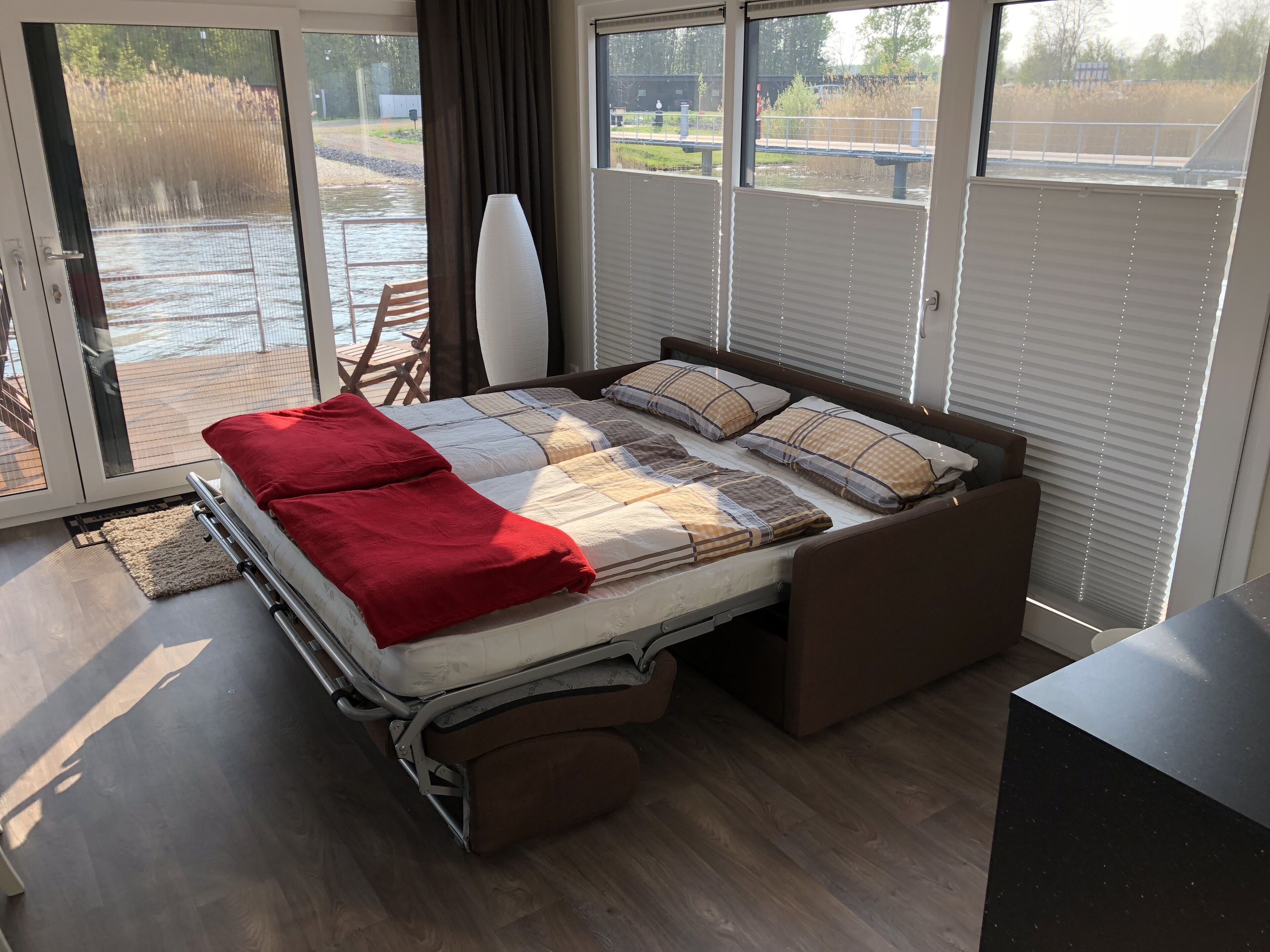 Un dormitorio con cama, una silla, un ventanal y vista a un cuerpo de agua.