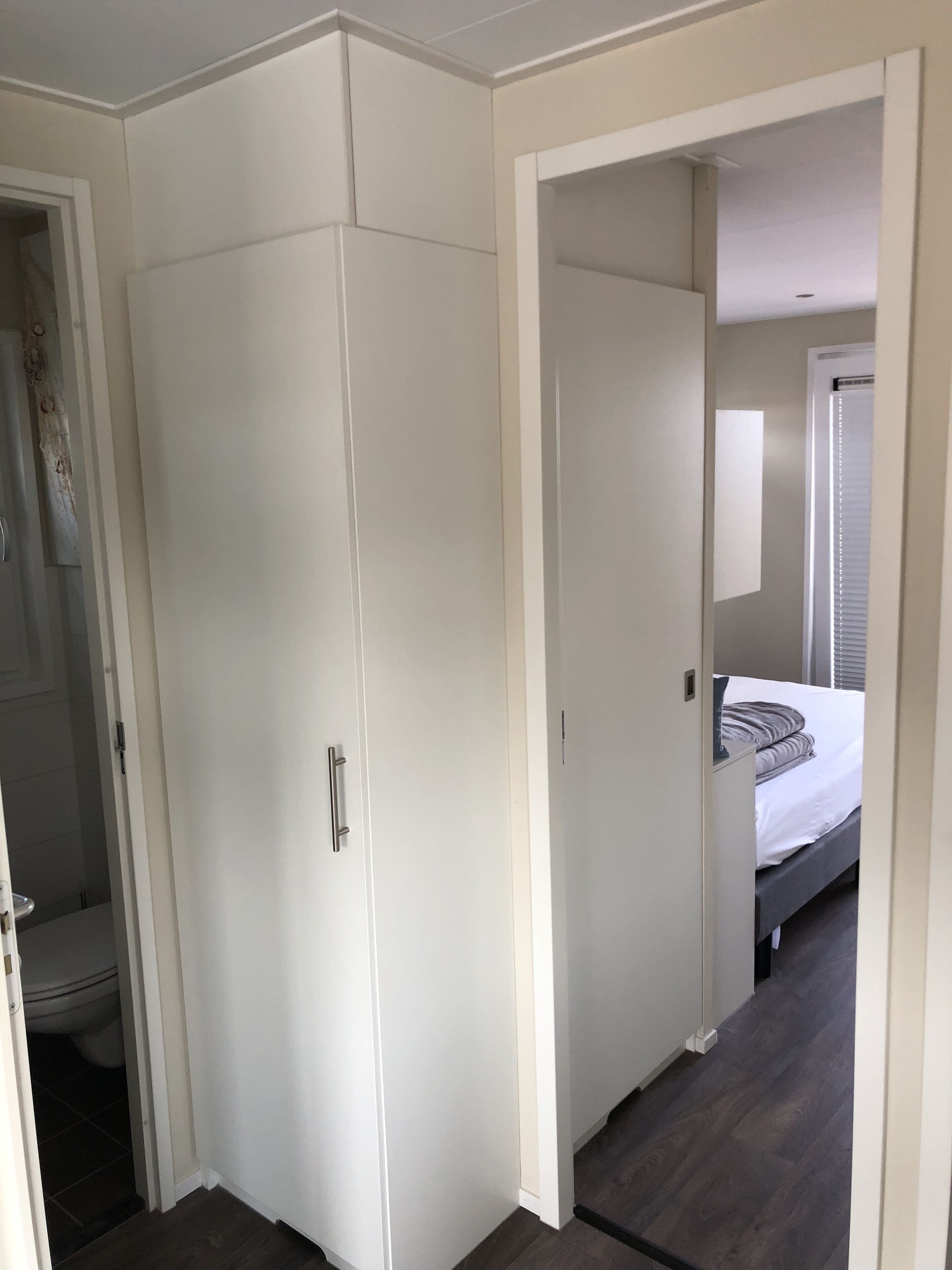 Une chambre à coucher comprenant un lit, une armoire et une porte donnant sur une autre pièce.