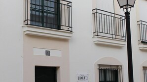 A building with a black door, a balcony with a metal railing, and a street lamp.