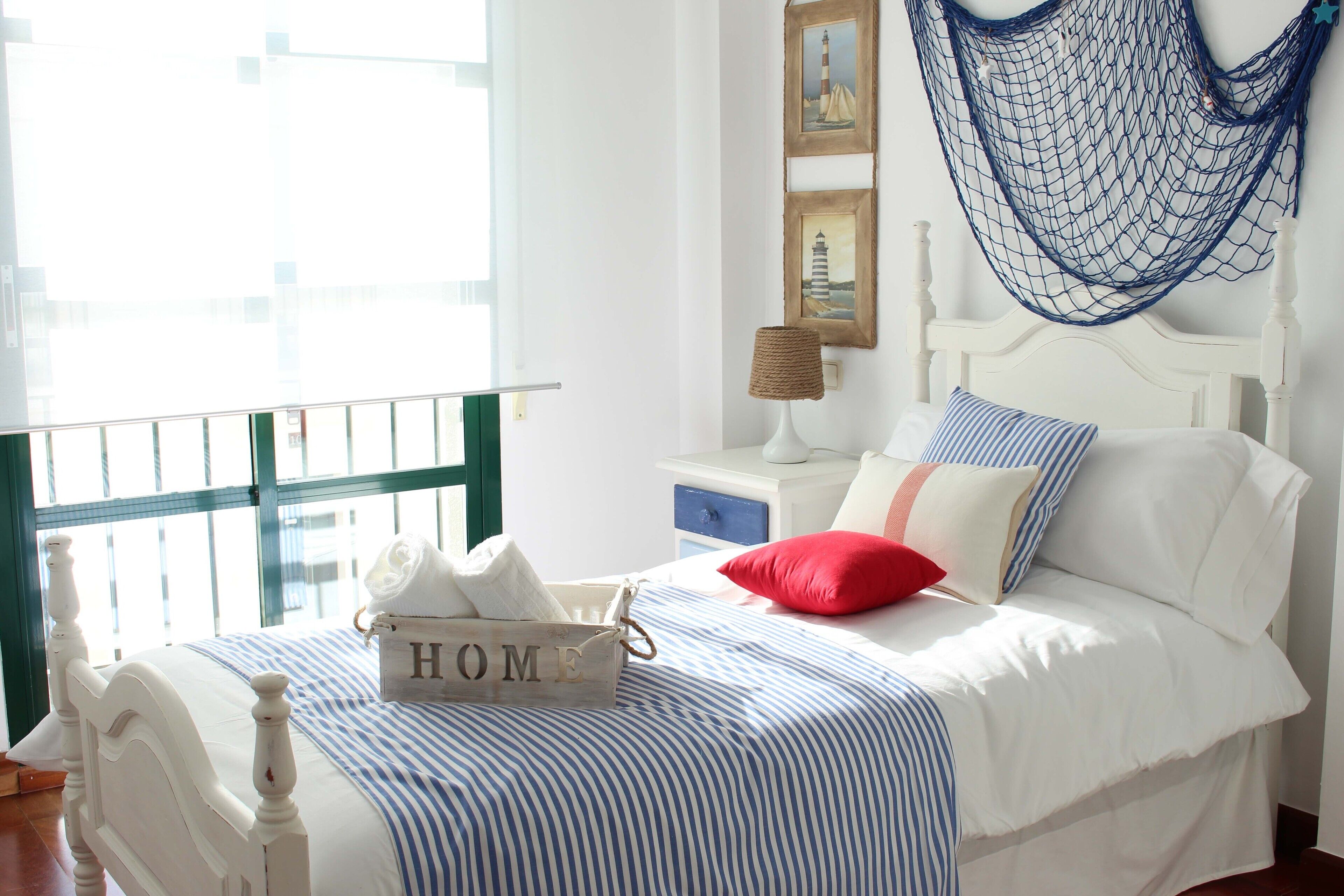 A neatly arranged bedroom with a bed, a bedside table, a lamp, and a window with a view.