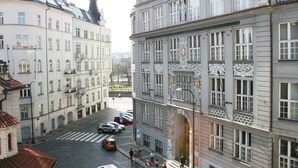 Vista de una calle con edificios, un paso de peatones y coches aparcados.
