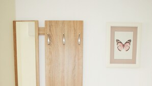 Un mueble de madera con dos cajones y un espejo, fijado a una pared con una obra de arte de mariposas enmarcada.