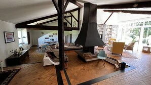 A spacious living area with a high ceiling, exposed wooden beams, a fireplace, and a view of a library. - "Paradise Found" Stunning Rural Setting - Pure Peace and Quiet 100% Guaranteed! (Ordan-Larroque)