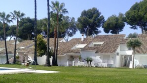 A residential area with white houses, a swimming pool, and palm trees. - New Andalusian house (Marbella)
