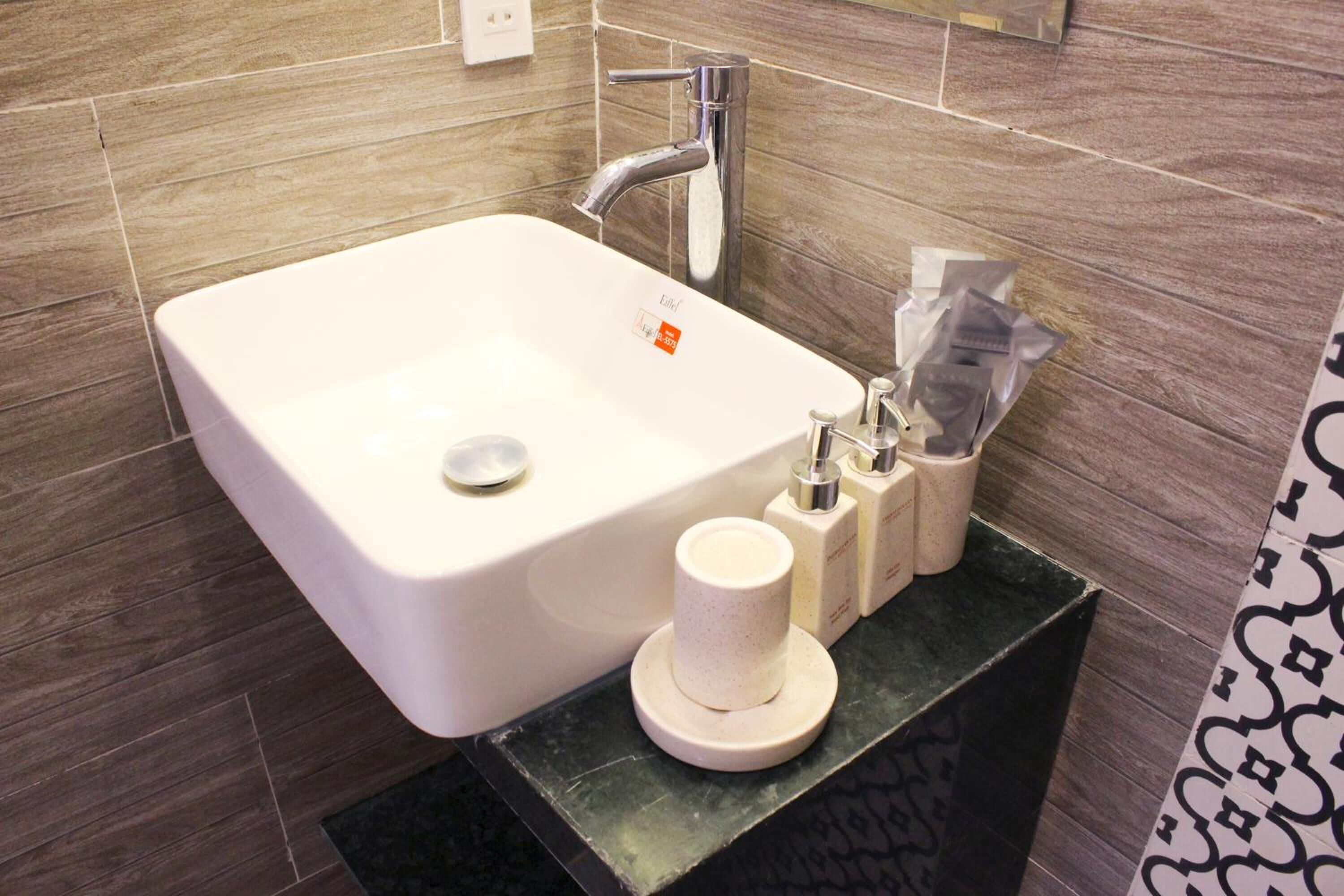 Un baño con un lavamanos blanco, un grifo y un dispensador de jabón.