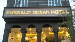 El exterior del Hotel Emerald Ocean, con un letrero llamativo, grandes columnas y una estatua al frente.