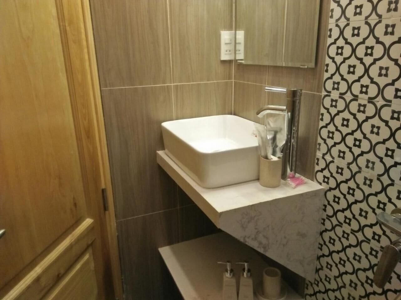 Egy fürdőszoba, amelyben fehér mosdókagyló, tükör és törölközőtartó található.