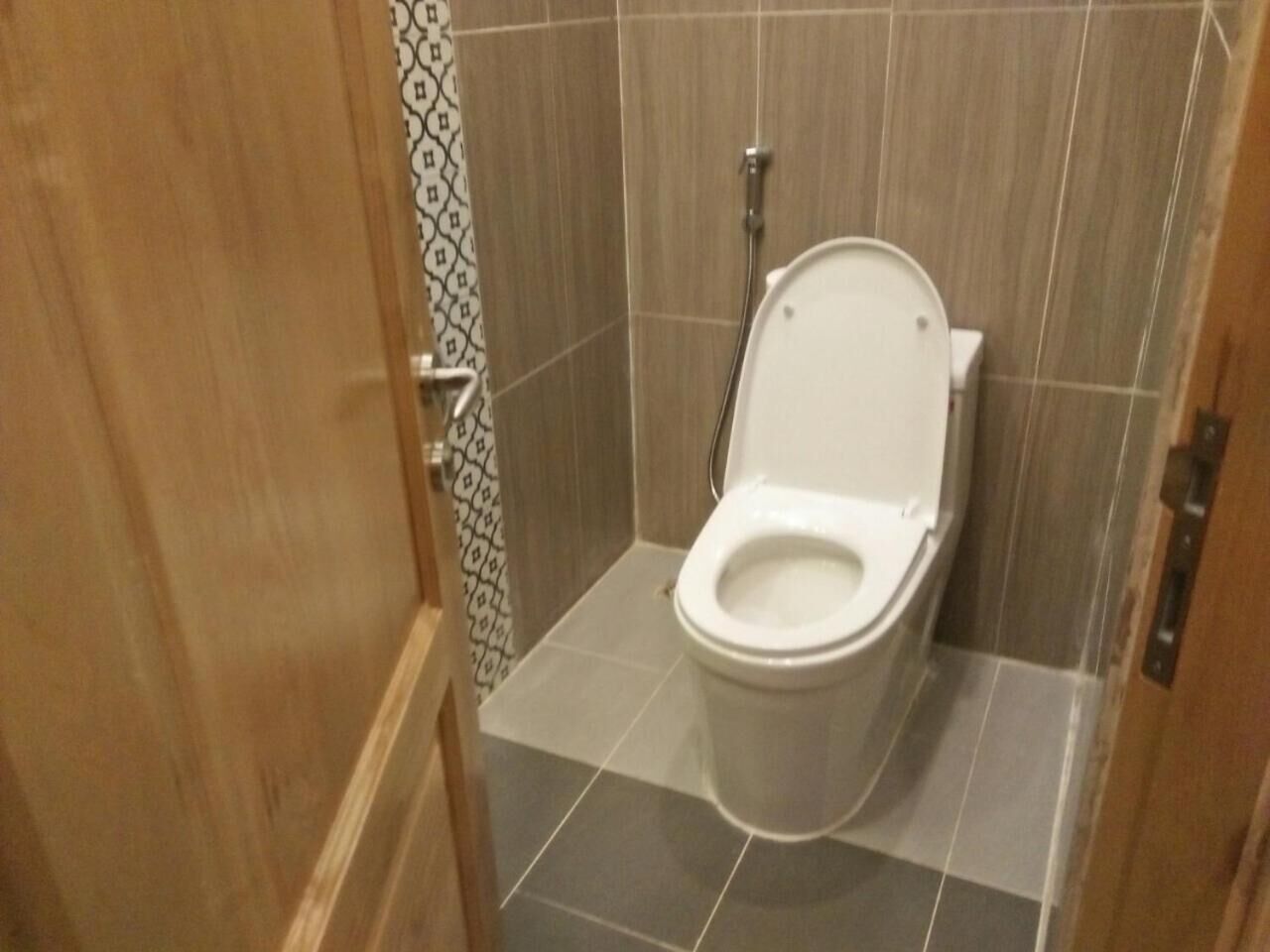 A small, tiled bathroom with a toilet and a shower.