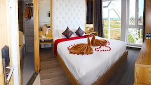 Habitación de hotel con cama, cómoda de madera, ventana con vistas y baño visible a través de una puerta abierta.