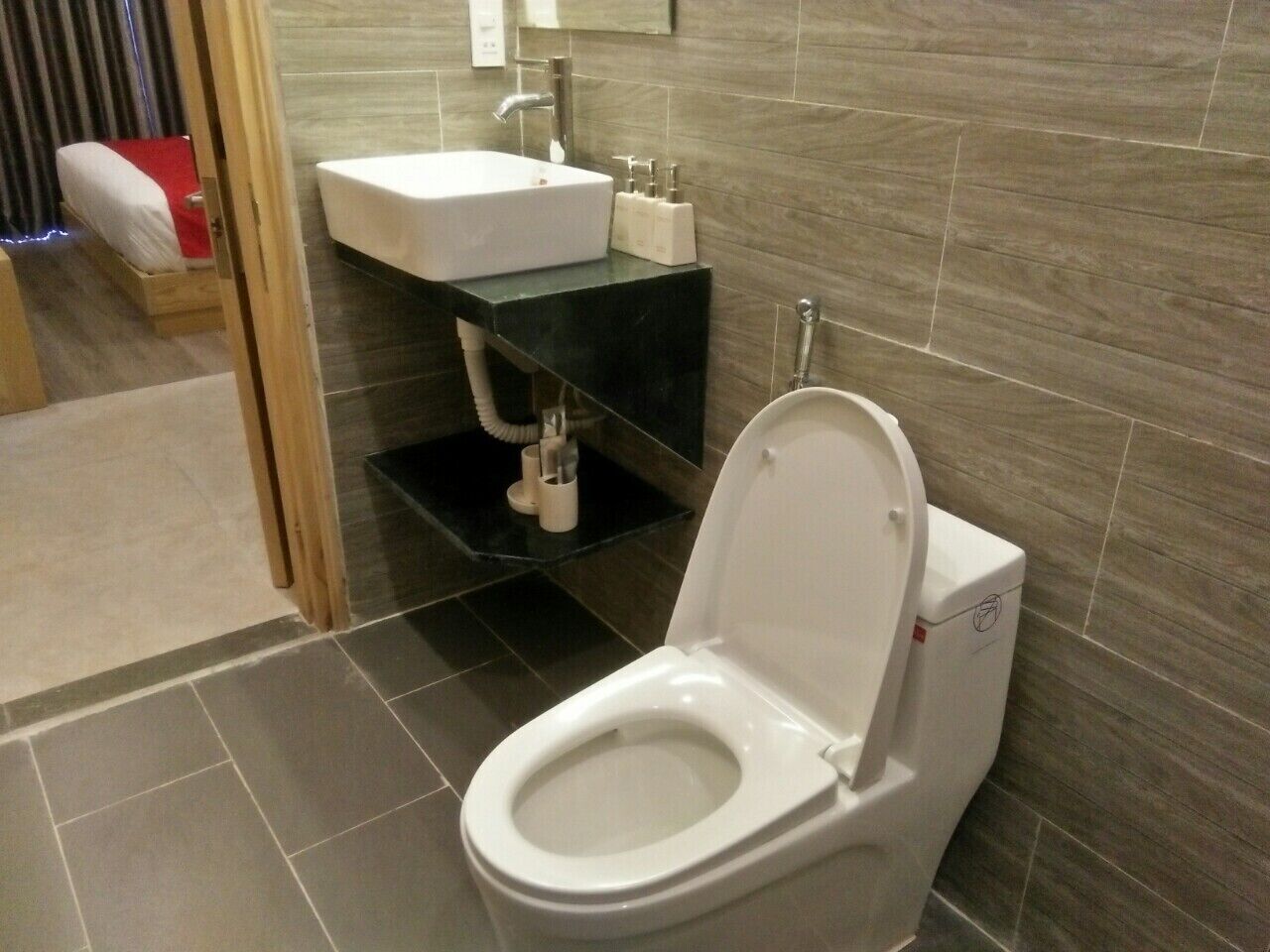 A modern bathroom with a white toilet, a sink with a black countertop, and a shower area.