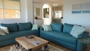 A living room with two teal sofas, a wooden coffee table, and patterned rugs. - Guesthouse -El campello-Alacant (El Campello)