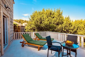 Ein Balkon mit zwei Holzliegen und einem Tisch mit einer Obstkiste.